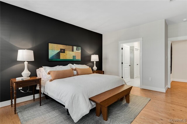 bedroom featuring connected bathroom and light hardwood / wood-style flooring