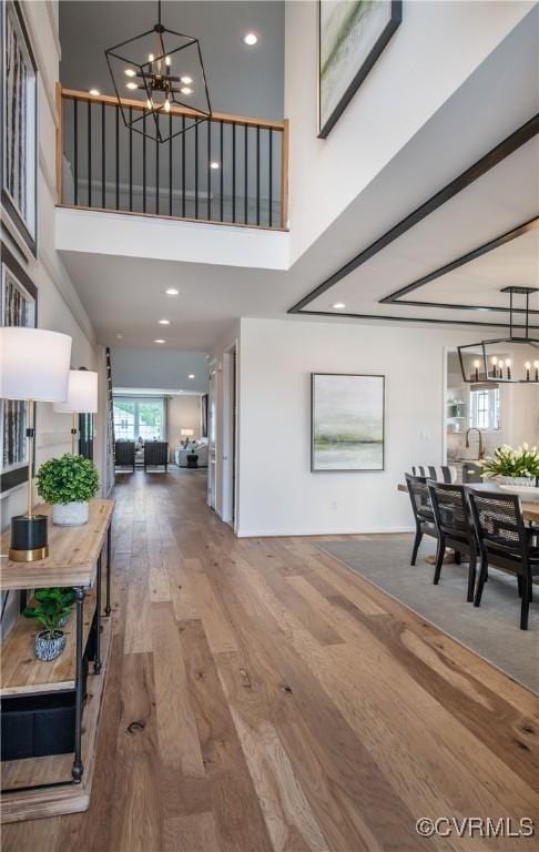 interior space featuring a towering ceiling, wood-type flooring, and a chandelier