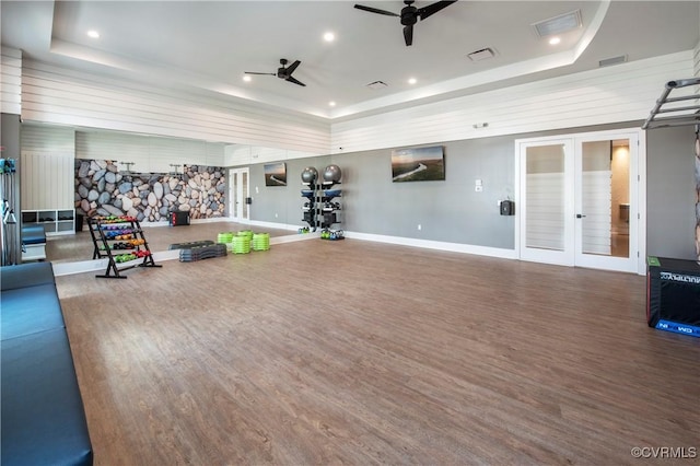 gym with hardwood / wood-style flooring, a raised ceiling, ceiling fan, and french doors