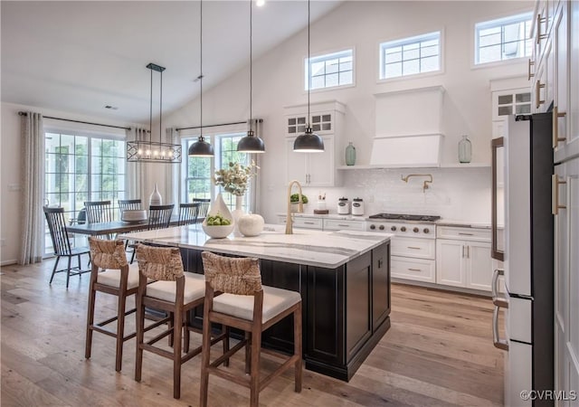 kitchen featuring white cabinetry, a center island, light stone counters, gas stovetop, and a kitchen bar