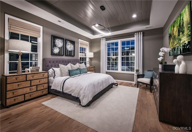 bedroom with a raised ceiling, hardwood / wood-style flooring, and wooden ceiling