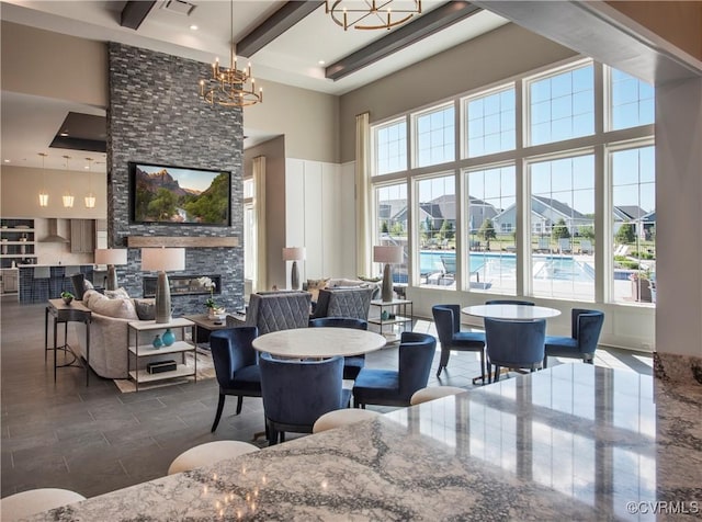 dining area with beamed ceiling, plenty of natural light, a chandelier, and a high ceiling