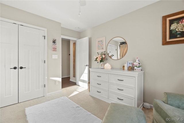 bedroom featuring light colored carpet, ceiling fan, and a closet