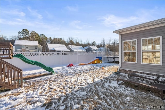 yard layered in snow featuring a playground and a trampoline