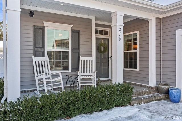 snow covered property entrance with a porch