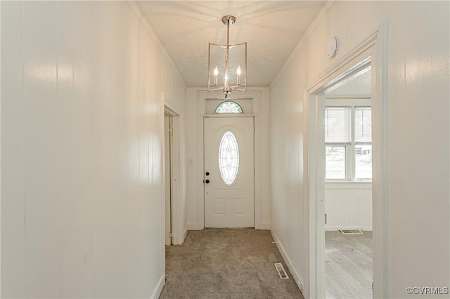 entryway with carpet flooring and a chandelier