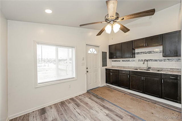 kitchen featuring dark brown cabinetry, sink, light wood-type flooring, ceiling fan, and decorative backsplash