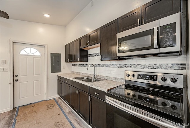 kitchen featuring sink, stainless steel appliances, electric panel, dark brown cabinetry, and decorative backsplash