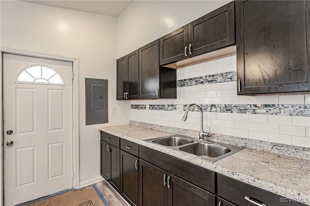 kitchen with dark brown cabinetry, electric panel, sink, and backsplash