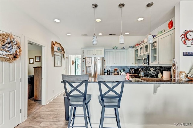 kitchen featuring appliances with stainless steel finishes, decorative light fixtures, decorative backsplash, light hardwood / wood-style floors, and kitchen peninsula