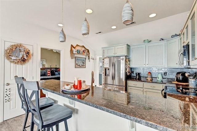 kitchen with pendant lighting, appliances with stainless steel finishes, a kitchen breakfast bar, and vaulted ceiling