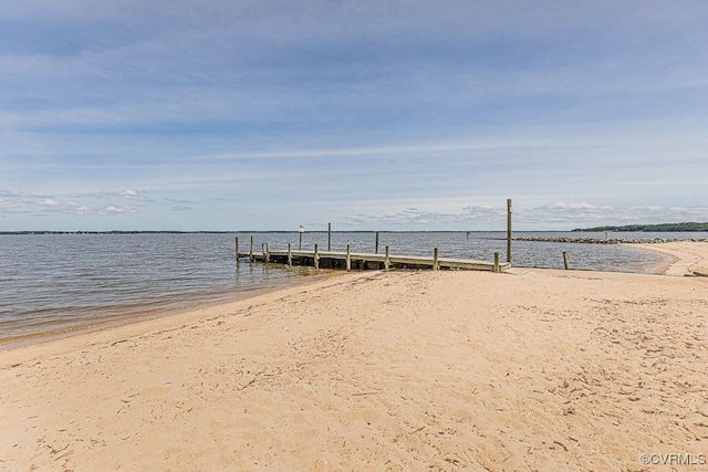 view of dock with a water view and a beach view