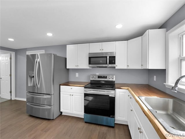 kitchen featuring white cabinetry, sink, stainless steel appliances, and butcher block counters