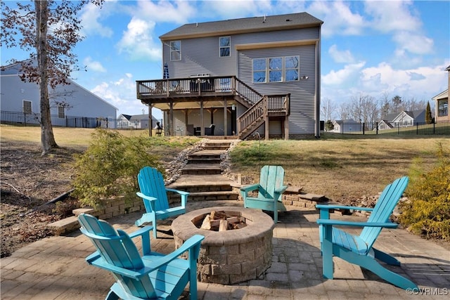 rear view of house with a patio, a wooden deck, a yard, and a fire pit