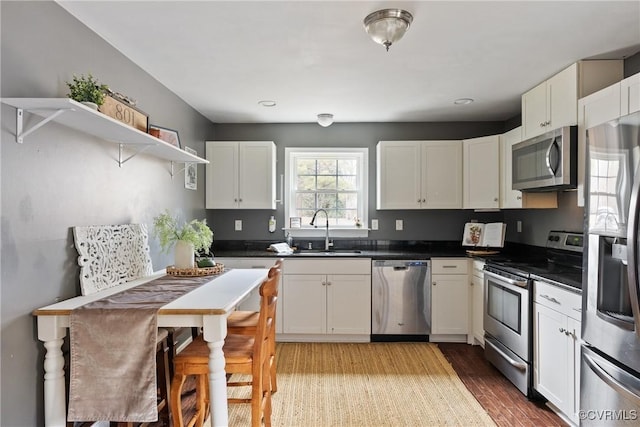 kitchen with sink, stainless steel appliances, white cabinets, and light wood-type flooring