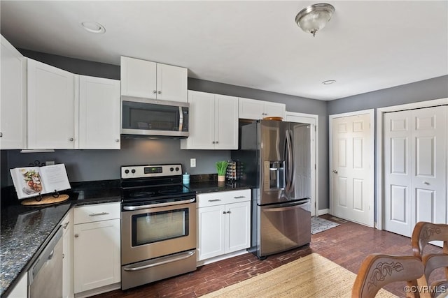 kitchen featuring stainless steel appliances, white cabinetry, dark wood-type flooring, and dark stone countertops