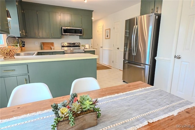 kitchen with sink, stainless steel appliances, and green cabinets