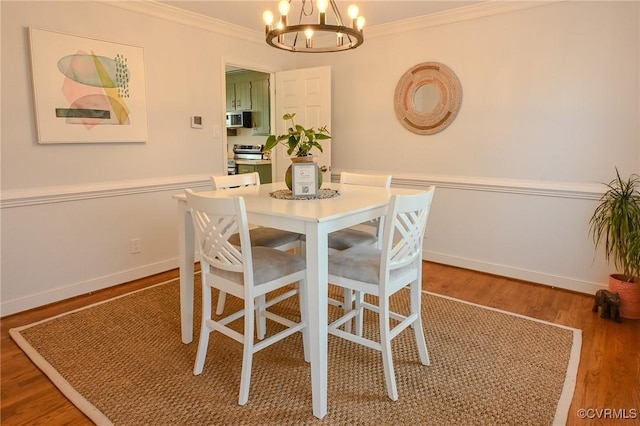 dining area featuring an inviting chandelier, ornamental molding, and hardwood / wood-style floors