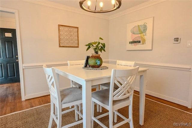 dining space with crown molding, wood-type flooring, and a chandelier