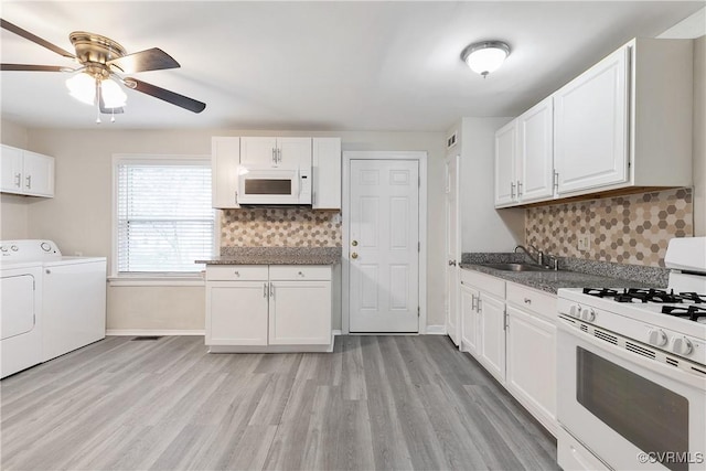 kitchen with sink, white cabinets, decorative backsplash, washing machine and dryer, and white appliances