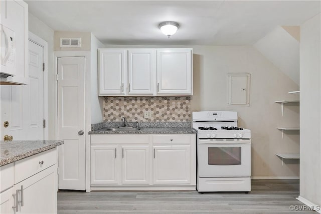 kitchen with tasteful backsplash, white cabinetry, light stone counters, light hardwood / wood-style floors, and white appliances