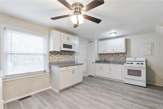 kitchen featuring white cabinetry, white appliances, plenty of natural light, and tasteful backsplash