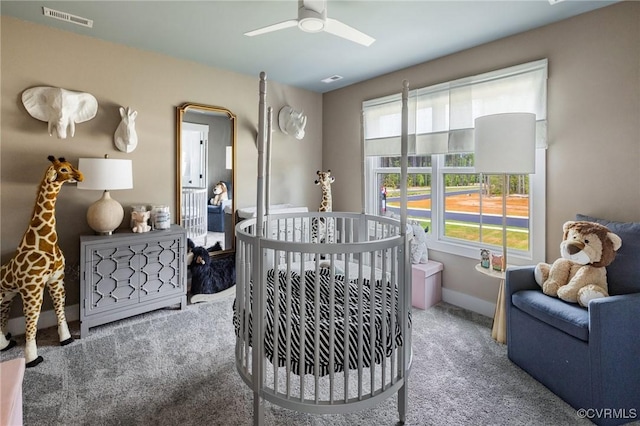 bedroom with a nursery area, ceiling fan, carpet, and multiple windows