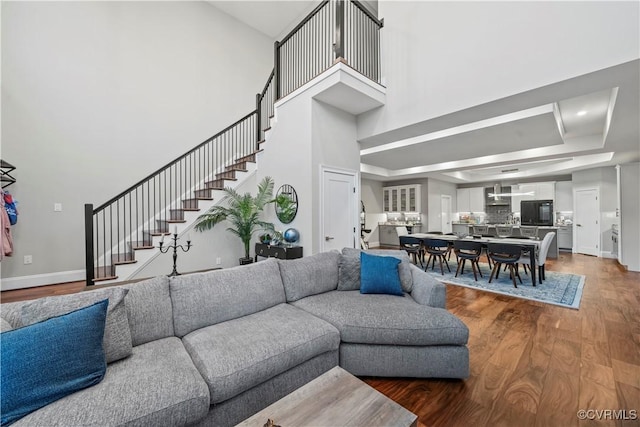 living room featuring a tray ceiling, hardwood / wood-style floors, and a towering ceiling