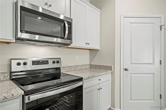 kitchen with white cabinetry, stainless steel appliances, and light stone countertops