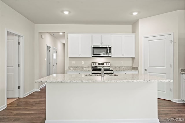 kitchen featuring white cabinetry, stainless steel appliances, light stone countertops, and a kitchen island with sink