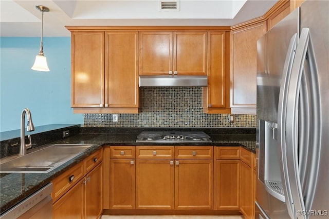 kitchen featuring sink, dark stone countertops, hanging light fixtures, stainless steel appliances, and tasteful backsplash