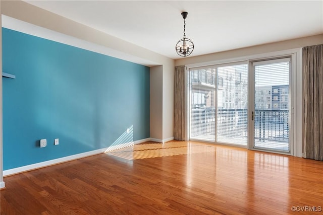 empty room with a notable chandelier and light hardwood / wood-style flooring