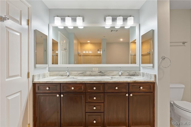 bathroom with vanity, toilet, and a tile shower