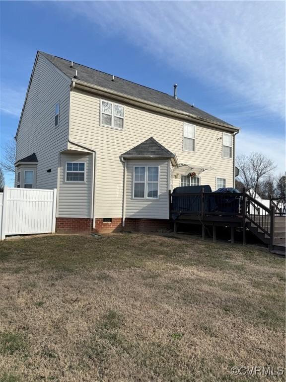 rear view of house featuring a wooden deck and a lawn