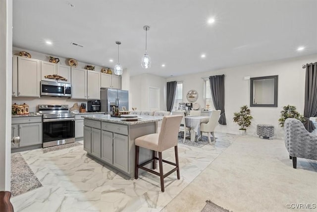 kitchen featuring gray cabinets, a kitchen island, a breakfast bar, decorative light fixtures, and stainless steel appliances