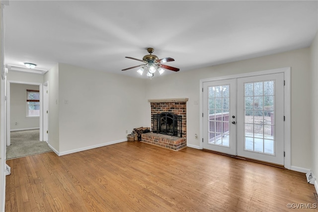 unfurnished living room featuring french doors, a fireplace, light hardwood / wood-style floors, and a wealth of natural light