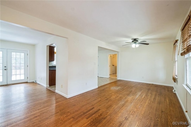 unfurnished living room featuring washer / clothes dryer, ceiling fan, light wood-type flooring, and french doors