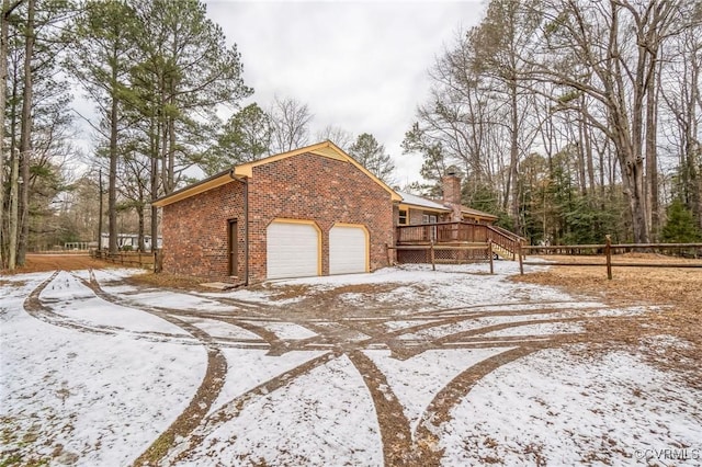 yard covered in snow featuring a garage and a deck