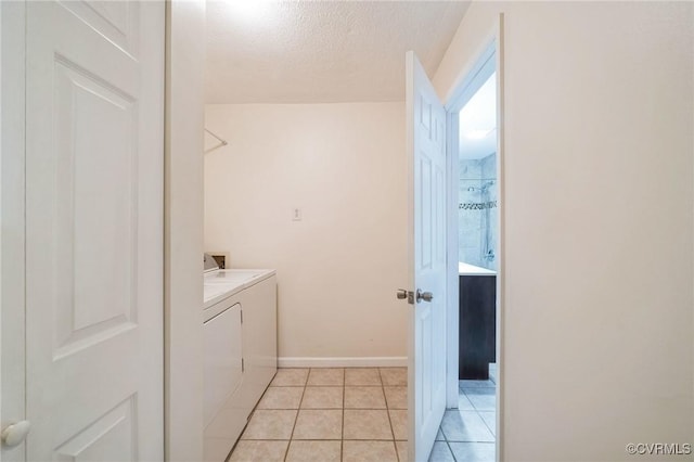 laundry area with washer and dryer, a textured ceiling, and light tile patterned flooring