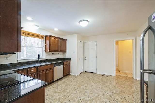 kitchen with dark stone countertops, light tile patterned floors, sink, and appliances with stainless steel finishes