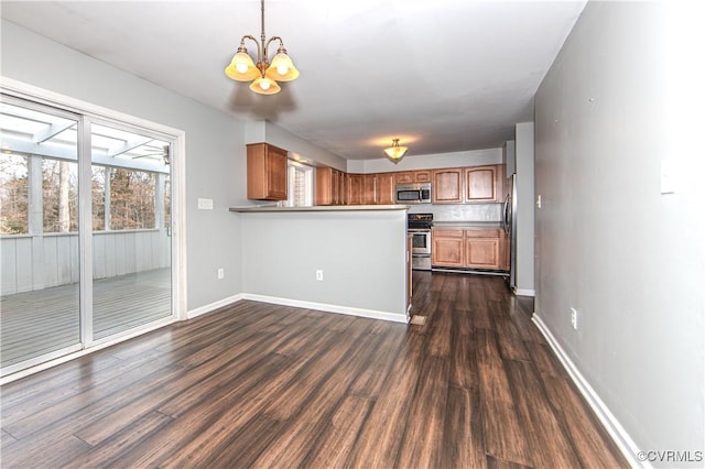 kitchen with pendant lighting, a chandelier, dark hardwood / wood-style flooring, kitchen peninsula, and stainless steel appliances