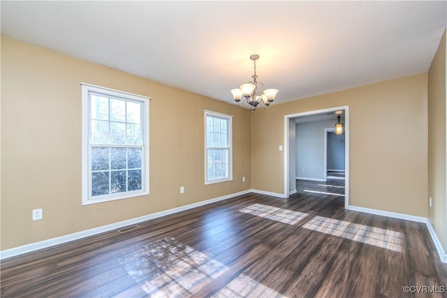 spare room featuring a notable chandelier and dark wood-type flooring