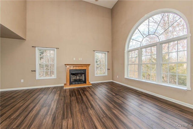 unfurnished living room featuring a towering ceiling and dark hardwood / wood-style floors