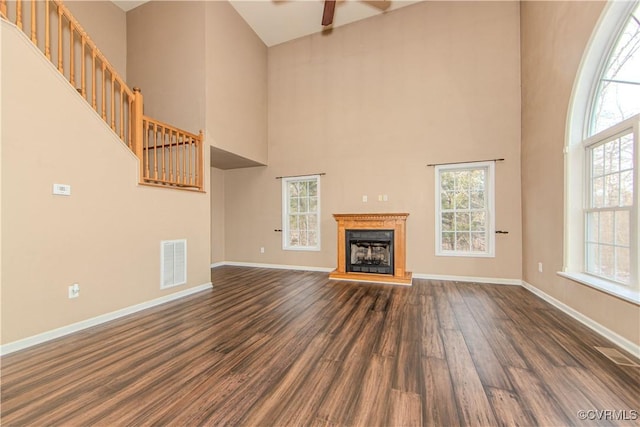 unfurnished living room with a high ceiling, dark hardwood / wood-style floors, and ceiling fan