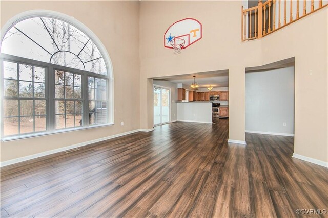 unfurnished living room with a towering ceiling, plenty of natural light, and dark hardwood / wood-style floors