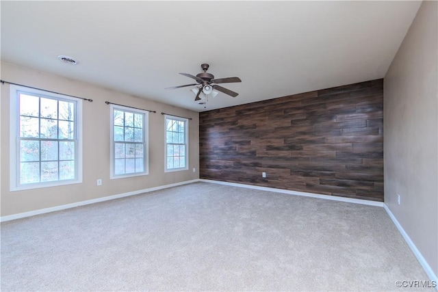 unfurnished room with dark colored carpet, ceiling fan, and wood walls