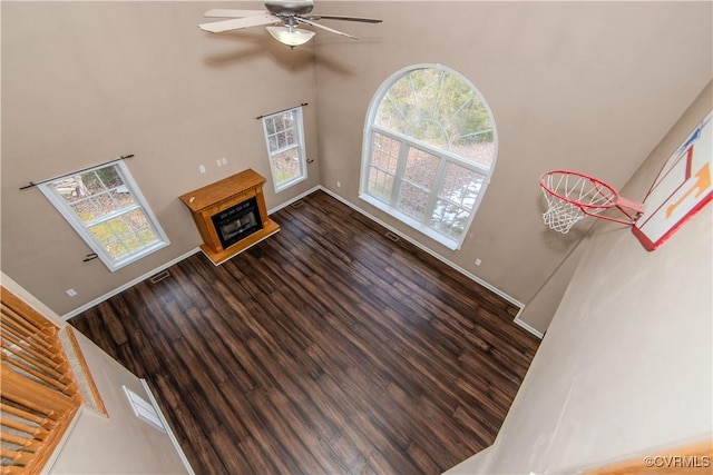 living room with a high ceiling, dark wood-type flooring, and ceiling fan