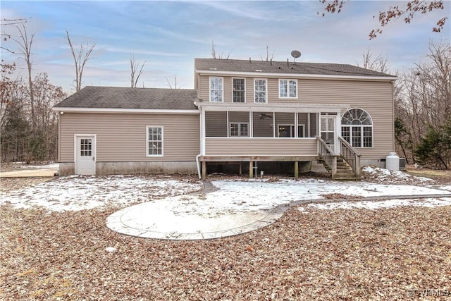 snow covered back of property featuring a sunroom