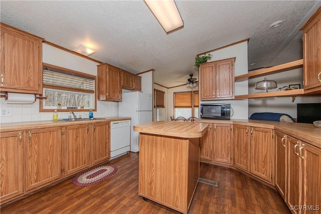 kitchen with crown molding, white appliances, dark wood-type flooring, a center island, and a textured ceiling