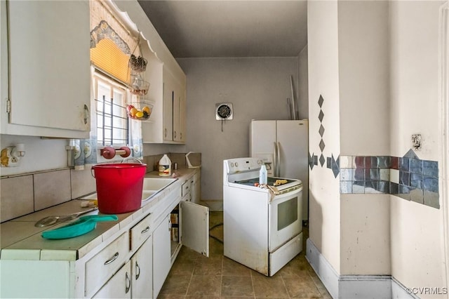 kitchen with sink, white appliances, light tile patterned floors, and white cabinets